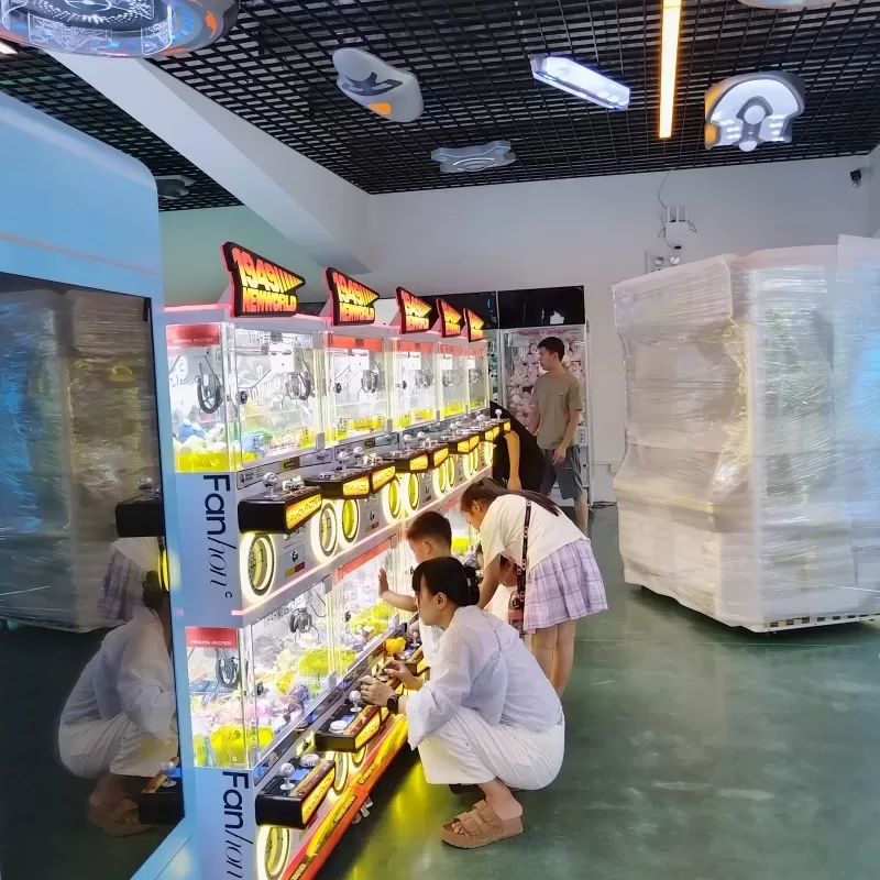 Commercial claw machine installation in a shopping mall entertainment area with colorful prizes