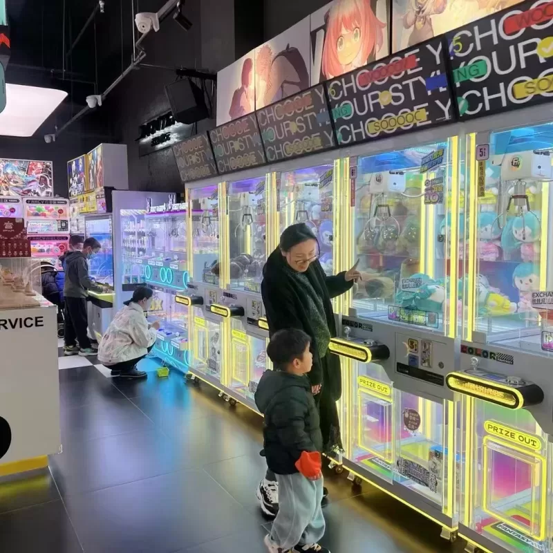 Commercial claw machine installation in a shopping mall entertainment area with colorful prizes